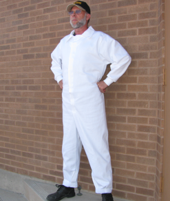 Worker modeling The FOD SUIT™ Safety Coveralls with brick background. Front view of white cotton pocketless coveralls.